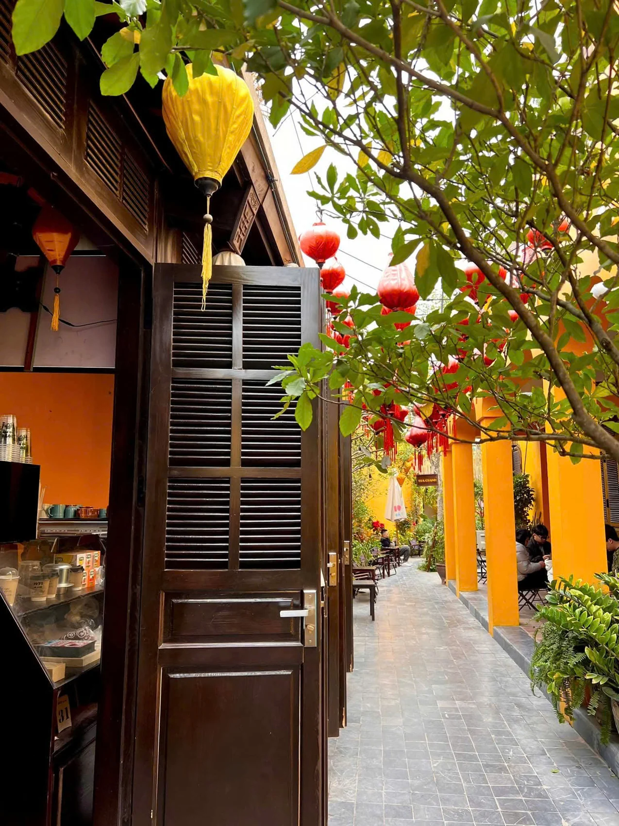 Lối đi giữa cửa gỗ, tán cây và hàng hiên